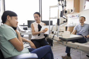 An optometrist explaining eye anatomy to a family, highlighting the importance of starting periodic eye checks early for children and adults.